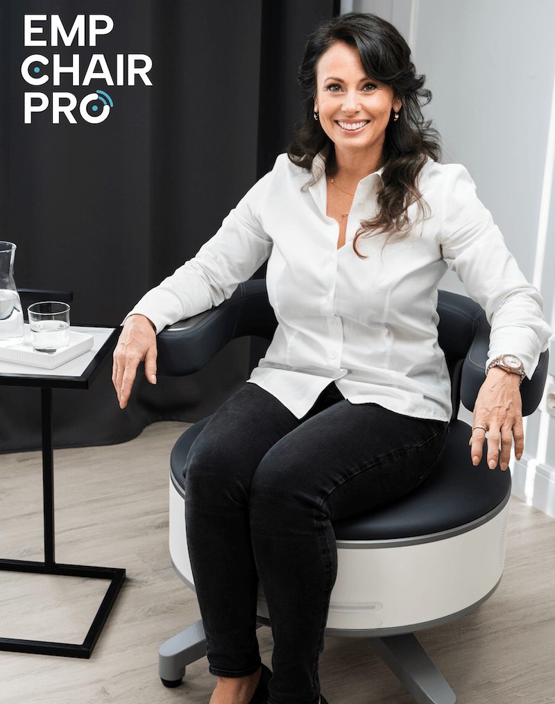 Frau sitzt bekleidet auf dem EMP Chair Pro zur Beckenbodenstimulation